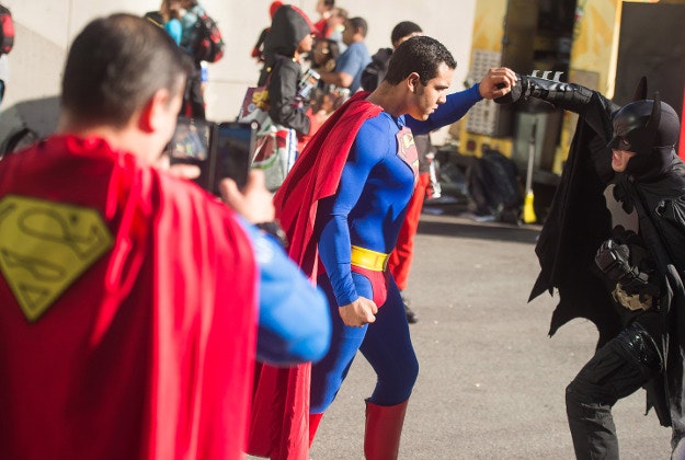 An attendee dressed as Superman takes a photo of a mock fight between Batman and another Superman during New York Comic Con at the Javits Center. 