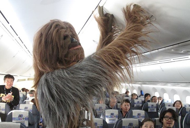 Chewbacca puts his luggage in the overhead storage on one of the first Star Wars-themed flights.