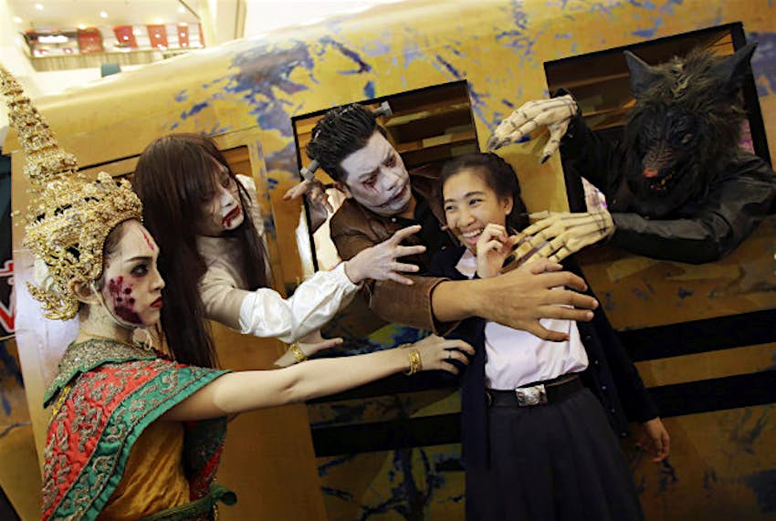 Travel News - thaihalloween A Thai woman smiles while poses for her friend take a picture with a ghosts costume for Halloween at shopping mall in Bangkok, Thailand.