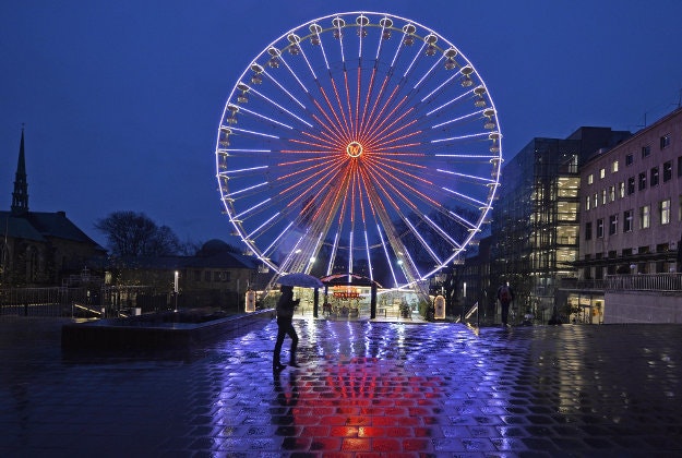 A Ferris wheel is reflected in the wet cobbles at the traditional Christmas market in Essen, Germany, Thursday, Nov. 19, 2015. 