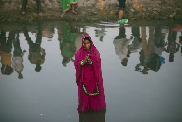 An Indian woman performs rituals at sunset in the Yamuna River during the Chhath Puja festival in New Delhi, India, Tuesday, Nov. 17, 2015. During Chhath, an ancient Hindu festival, rituals are performed to thank the Sun god for sustaining life on earth. 