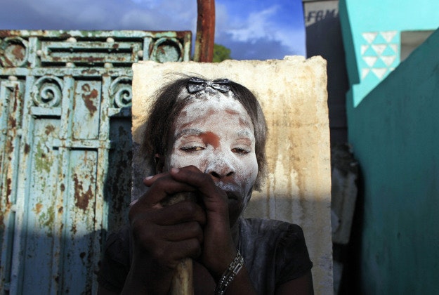 A woman in the role of a spirit known as a "Gede" looks on while holding a human bone in her hands during Day of the Dead celebrations at the National Cemetery in Port-au-Prince, Haiti, Sunday, Nov. 1, 2015. Day of the Dead traditions coincide with All Saints Day and All Souls Day on Nov. 1 and 2.