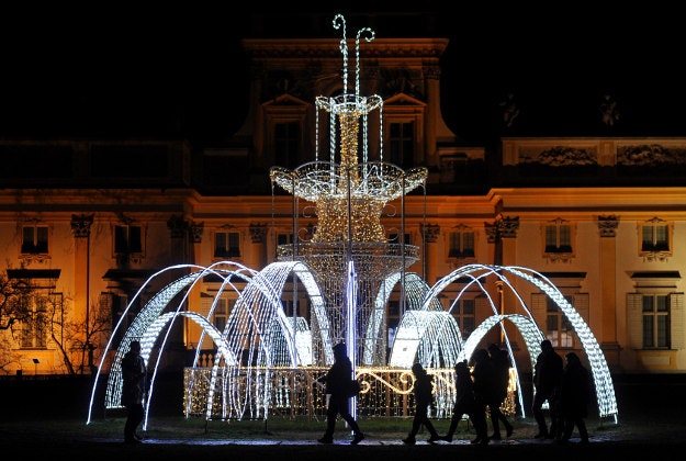 People visit the Royal Garden of Light in Warsaw, Poland, Sunday, Nov. 29, 2015. The Royal Garden of Light, with plants and decorations made of thousands of colorful diodes, is a winter exhibition that brightens up the garden surrounding the Wilanow Palace, seen in the background.