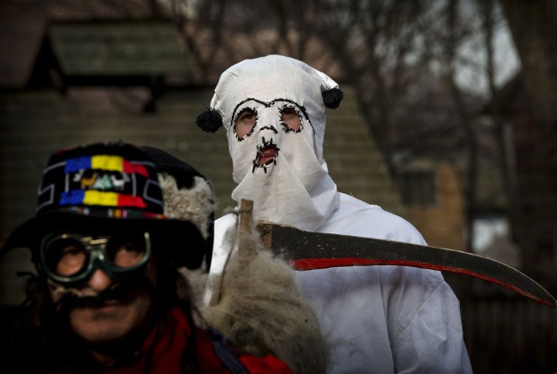 Men wearing masks prepare to perform in a show of winter traditions at the Village Museum in Bucharest, Romania, Sunday, Dec. 13, 2015. In pre-Christian rural traditions, dancers wearing colored costumes or animal furs, toured from house to house in villages singing and dancing to ward off evil. 