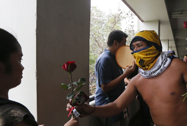 A naked student hands a rose to a student as he and about two dozen members of the Alpha Phi Omega fraternity run naked around the Arts and Sciences building in the traditional "Oblation Run" to dramatize the important issues of the year at the University of the Philippines in suburban Quezon city, northeast of Manila, Philippines, Monday, Dec. 14, 2015. Hundreds of students turned out to watch the traditional annual run. 