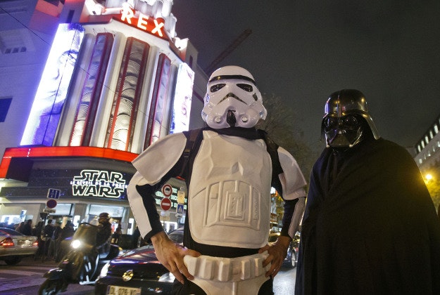 People dressed as a Stormtrooper and Darth Vader pose outside the Grand Rex movie theater for photographers prior to a screening of "Star Wars: The Force Awakens"in Paris, Wednesday, Dec. 16, 2015. 