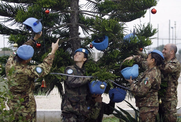 Italian U.N. peacekeepers decorate a Christmas tree with helmets at their base in the southern village of Chamaa, Lebanon, Thursday, Dec. 17, 2015.