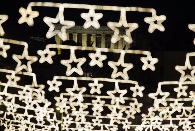 The spotlit ancient Parthenon temple on the Acropolis appears behind strings of Christmas lights in central Athens, on Thursday, Dec. 17, 2015. Greeks are set to celebrate their sixth Christmas of austerity, as the country braces for more cutbacks demanded by international creditors in return for Greece's third bailout deal, signed in the summer. 