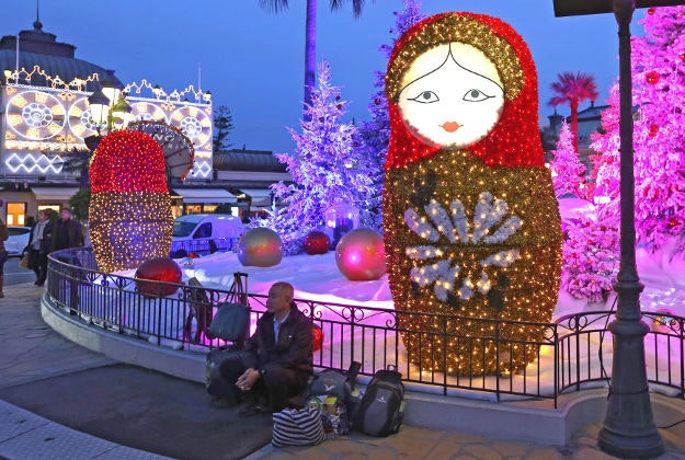 A tourist sits next to Christmas decorations in front of the Monte Carlo Casino, Thursday, Dec. 17, 2015, in Monaco. Every year, Christmas decorations adorn Monaco city.