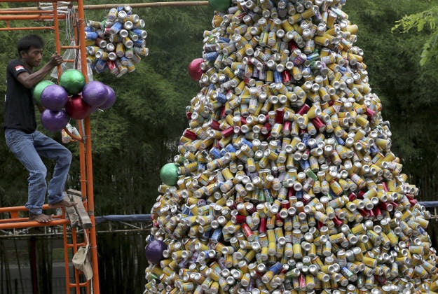A worker arranges about ten thousand discarded beverage cans to form a Christmas tree in front of a church in Jakarta, Indonesia, Friday, Dec. 18, 2015. 