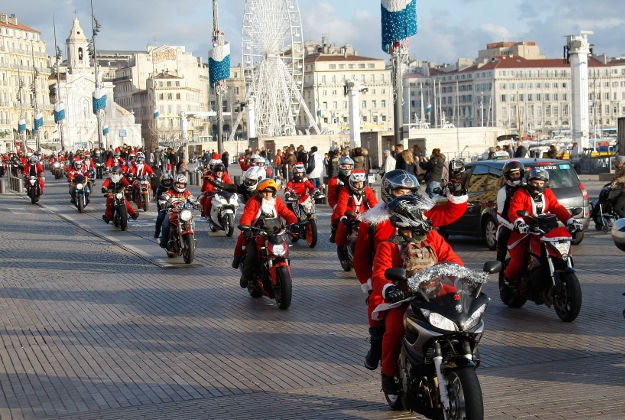Motorcyclist members of Sliders Massilia Motor Club, wear Santa Claus costumes, as they ride on the Old-Port, in Marseille, southern France, Sunday, Dec. 20, 2015. Every rider will bring a new toy for the children hospitalized in the public hospitals of Marseille area. 