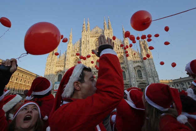 Men and women wearing Santa Claus costumes release balloons on the occasion of a charity initiative aimed at raising funds to help abandoned children in front of the Duomo gothic cathedral, in Milan, Italy, Sunday, Dec. 20, 2015. 