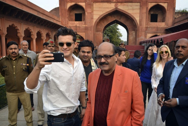 In this Sunday, Dec. 20, 2015, photo, British actor Orlando Bloom, front left, takes a selfie as Indian lawmaker Amar Singh, front right, watches on arrival at the Taj Mahal in Agra, India. Indian officials say Bloom has arrived in New Delhi after being turned away a day earlier because he did not have a valid visa. 