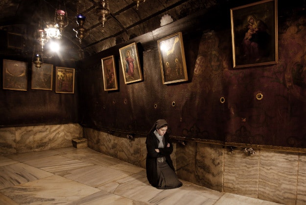 A nun prays inside the Grotto at the Church of the Nativity, believed to be the birthplace of Jesus Christ, in the biblical West Bank city of Bethlehem, Monday, Dec. 21, 2015. 