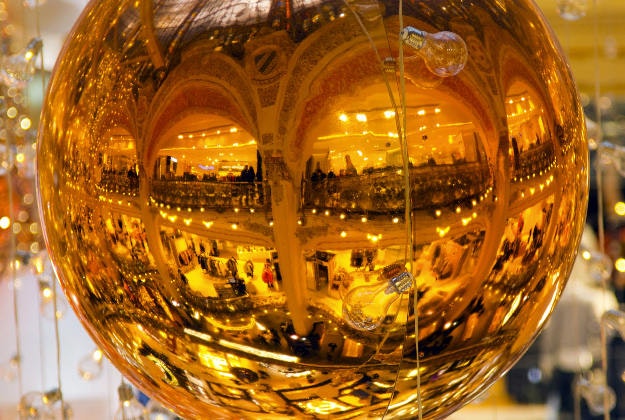 A Paris department store is reflected in a huge Christmas tree ball, Tuesday, Dec. 22, 2015. The decorations are traditionally put up late November each year for Christmas. 
