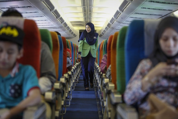 In this Dec. 22, 2015, photo, a Rayani Air flight crew walks down the aisle on board before departure at Kuala Lumpur International Airport 2 in Sepang, Malaysia. Malaysia?s Rayani Air took to the skies over the weekend with a clear bailiwick. It is the country?s first Islamic airline, offering flights that adhere to Islamic rules including prayers, no-alcohol, no-pork meals, and a strict dress code for Muslim female flight attendants