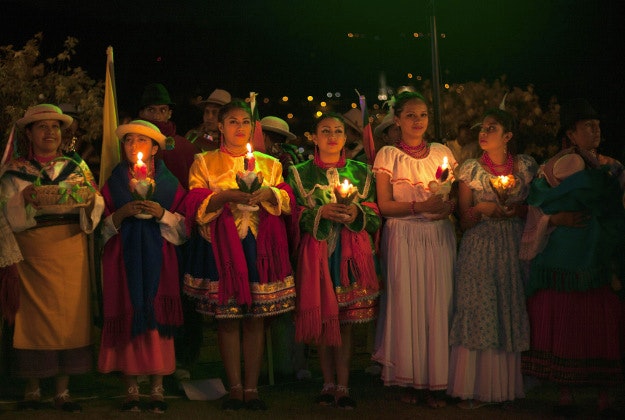 Dancers from La Magdalena community hold candles as they pray on the seventh day of the "Novena" in Quito, Ecuador, Tuesday, Dec. 22, 2015. The nine-day event leads up to Christmas eve, a time when families and friends gather to pray, eat and sing Christmas carols. The tradition also showcases traditional Ecuadorian clothing and dances. 