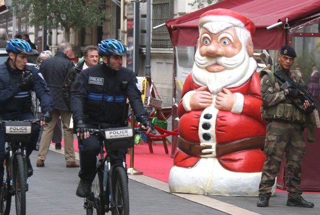 French police officers and a French soldier patrol near a Santa Claus model, in a street in Nice, southeastern France, Wednesday, Dec. 23, 2015. France's interior minister says the government will tighten security around Christmas, amid continued concerns about potential extremist violence after deadly attacks last month.