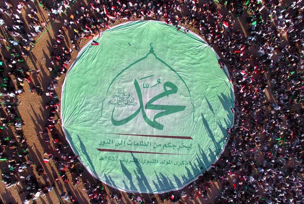 Shiite rebels, known as Houthis, stand around a large banner with Arabic writing that reads,"Muhammed" during the celebration of Moulid Al-Nabi, the birth of Islam's Prophet Muhammad in Sanaa, Yemen, Wednesday, Dec. 23, 2015. 