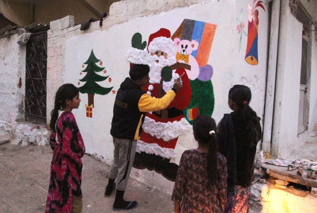 A boy paints a Santa Claus on a wall in Christian neighborhood in Karachi, Pakistan, Wednesday, Dec. 23, 2015 for the upcoming Christmas celebrations. 