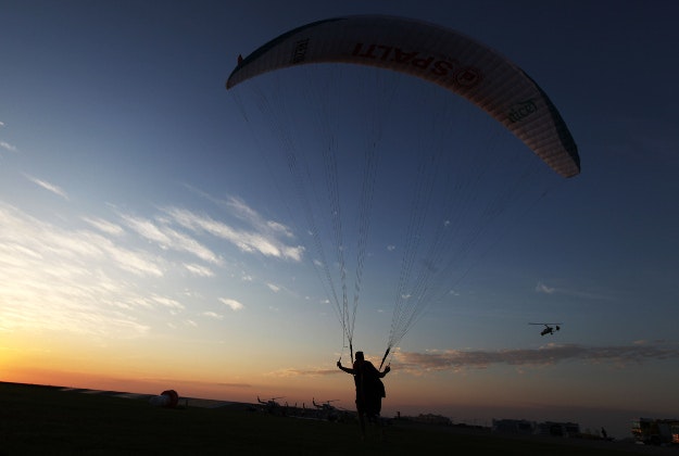 A paraguilder watches a gyrocopter fly at sunset at the World Air Games in Dubai, United Arab Emirates, on Sunday, Dec. 6, 2015. The World Air Games includes precision aerobatics, skydiving and hot air balloon competitions. 