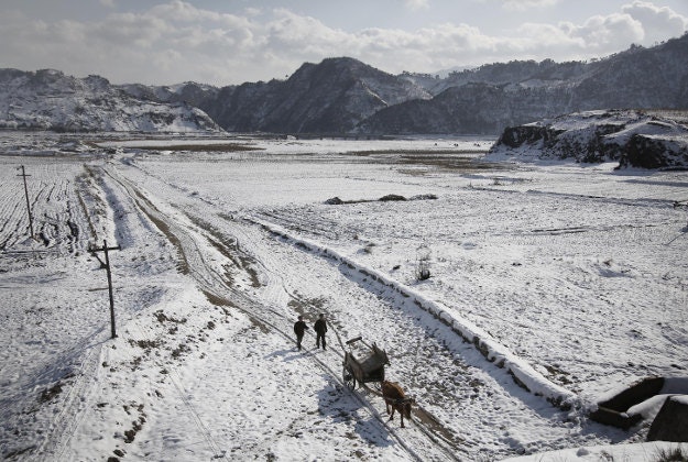 Two farmers walk between snow covered farm fields on Thursday, Dec. 3, 2015, in Kujang county, North Pyongan, North Korea where the winter season has started. 