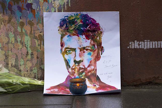 Travel News - 1 A painting and a candle are left below a mural of David Bowie on the wall of a Morley's store in Brixton, London, the singers birthplace, after the rock star died following an 18-month battle with cancer.