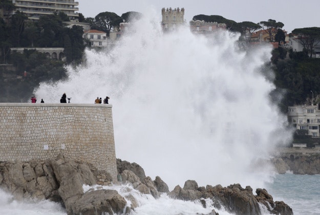 People look at a wave from Mediterranean sea in Nice, southeastern France during a high tide, Monday, Jan. 11, 2016. Temperatures in the area rose to 18 Celsius (64 Fahrenheit). 