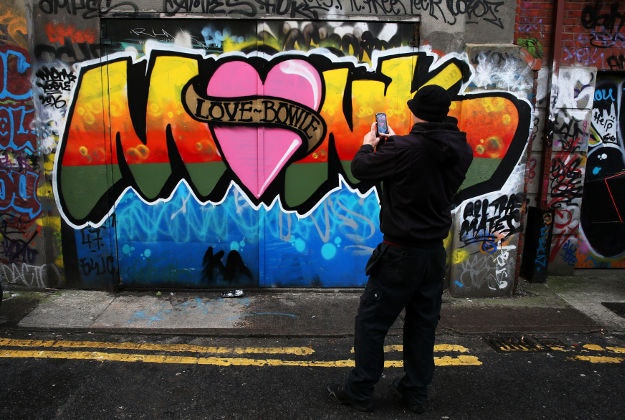 A passerby takes a photo of a graffiti mural dedicated to David Bowie in Dublin's city centre, following the announcement of his death on monday. 