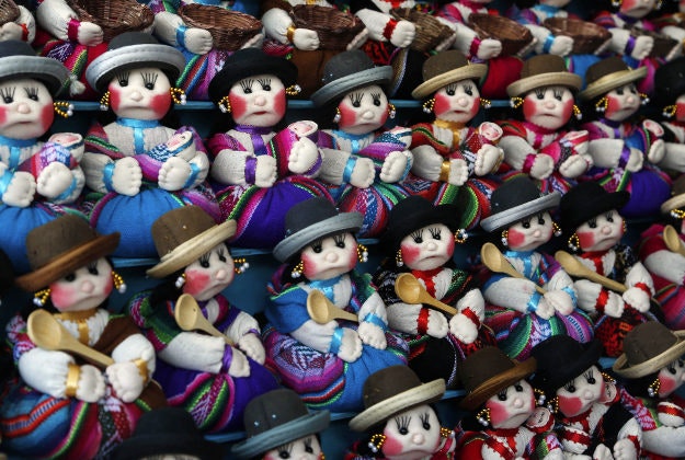 A woman sells miniature rag dolls in the likeness of "cholitas" at the Alasita Fair in La Paz, Sunday, Jan. 24, 2016. Following ancient Aymara indigenous tradition, "Alasita" is an Aymaran word that means "buy me," and is the name of the annual fair where people buy miniature items that represent things they hope to attain within the year. People buy the cholita dolls for decoration. 