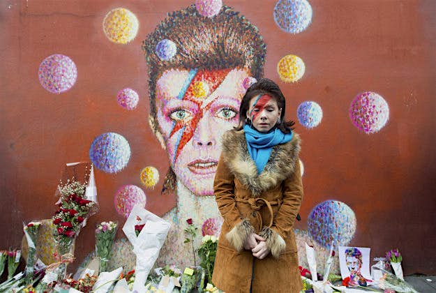 Travel News - 3 Lowri (surname not given), with her face painted as Ziggy Stardust, by a mural of David Bowie on the wall of a Morley's store in Brixton, London, the singers birthplace, after the rock star died following an 18-month battle with cancer.