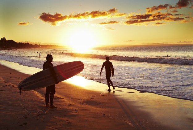 Surfer on beach at sunset, Noosa Heads in Queensland, Australia. 