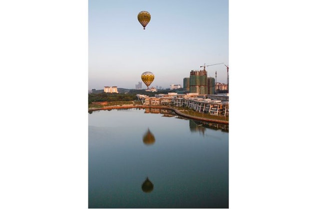 Hot air balloons fly past a construction site in Putrajaya, Malaysia, Tuesday, Jan. 12, 2016