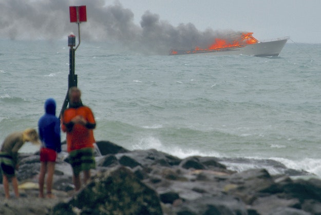 eople stand on the shoreline as a tourist boat carrying 60 people burns out at sea off the coast of Whakatane, New Zealand, Monday, Jan 18, 2016.