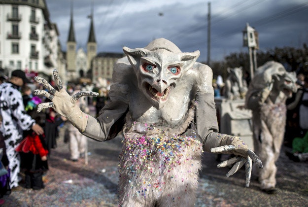 Masked revelers parade through the streets during the start of the carnival in Lucerne, Switzerland, Monday, Feb. 8, 2016. 