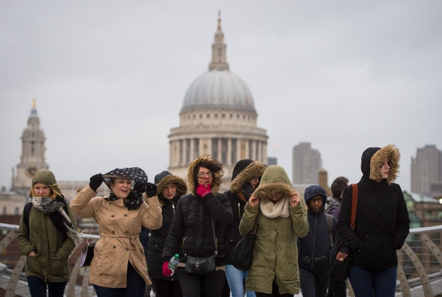 People experience high winds as they cross the Millennium Bridge in London, as winds of nearly 100mph battered parts of Britain after Storm Imogen slammed into the south coast bringing fierce gusts and torrential downpours. PRESS ASSOCIATION Photo. Picture date: Monday February 8, 2016. Gales and heavy rain have forced road closures and delays to rail services, with airports warning flights may be disrupted. 