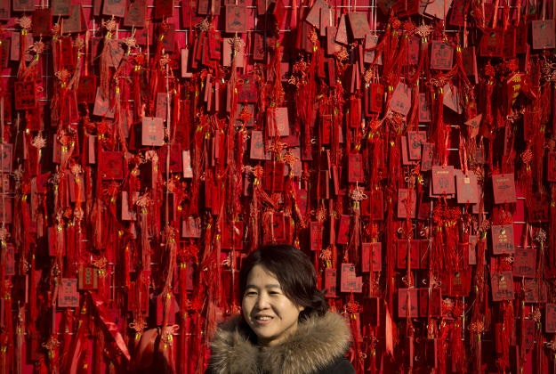 A woman stands in front of a fence covered in blessing tablets at the Dongyue Temple during the second day of the Chinese Lunar New Year in Beijing, Tuesday, Feb. 9, 2016. Millions of Chinese are celebrating the Lunar New Year, which marks the Year of the Monkey on the Chinese zodiac. 