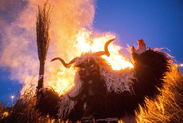 A reveler wearing sheep fur costume is seen in front of a bonfire on which they burn a coffin symbolizing winter during the closing ceremony of the traditional carnival parade in Mohacs, 189 kms south of Budapest, Hungary, Tuesday, February 9, 2016. The carnival parade of people, the so-called busos, dressed in such costumes and frightening wooden masks is traditionally held on the seventh weekend before Easter to drive away winter. 