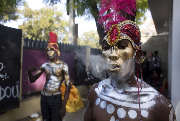 A Carnival performer smokes a cigarette before the start of the last day of Carnival celebrations in Port-au-Prince, Haiti, Tuesday, Feb. 9, 2016. Political tensions haven't stopped the Haitian capital's annual Carnival, but the uncertainty led to the cancellation of the first day of festivities and put such a damper on the party that a number of top bands have pulled out. There have been relatively few decorated floats, a scarcity of sponsors and many Haitians say they are staying away from the capital’s annual celebration this year out of security concerns. 