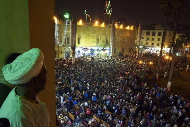 In this Tuesday, Feb. 9, 2016 photo an Egyptian watches the site of al-Hussein mosque as thousands celebrate Moulid al-Hussein, a Sufi gathering which commemorates the birth of the Muslim Prophet Muhammad's grandson, in Cairo, Egypt. The event attracts thousands of Muslims from all over the country to the mosque and shrine named for him. 