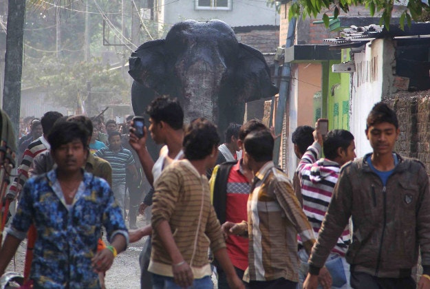 A wild elephant that strayed into the town moves through the streets as people follow at Siliguri in West Bengal state, India, Wednesday. The elephant had wandered from the Baikunthapur forest on Wednesday, crossing roads and a small river before entering the town. The panicked elephant ran amok, trampling parked cars and motorbikes before it was tranquilized.