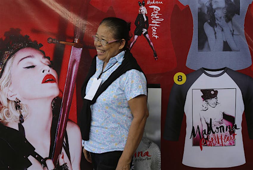 Travel News - 11255001-1 A Filipino woman passes by posters of Madonna outside the venue where she will be holding a concert in suburban Pasay, south of Manila, Philippines on Wednesday, Feb. 24, 2016. Pop star Madonna made a surprise visit to two Manila shelters for orphans and street children, taking selfies with kids a day before the start of her two-night concert stint in the Philippine capital.