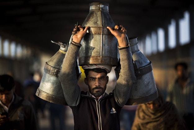 Indian milkman carries milk canisters early morning in Ghaziabad train station, on the outskirts of New Delhi, India, Wednesday, Feb. 24, 2016. India is the world's largest producer of milk and also the largest consumer. 