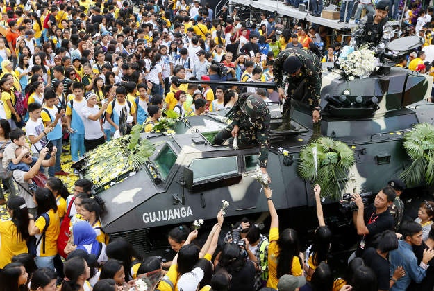 Students hand flowers to soldiers during the 30th anniversary celebration of the "People Power Revolution" that toppled the 20-year-rule of the late strongman Ferdinand Marcos and helped install Corazon "Cory" Aquino to the presidency Thursday, Feb. 25, 2016 at suburban Quezon city northeast of Manila, Philippines. The four-day People Power saw hundreds of thousands of Filipinos trooping to EDSA Avenue fronting two military camps to lend support to mutinous soldiers who broke away from Marcos.