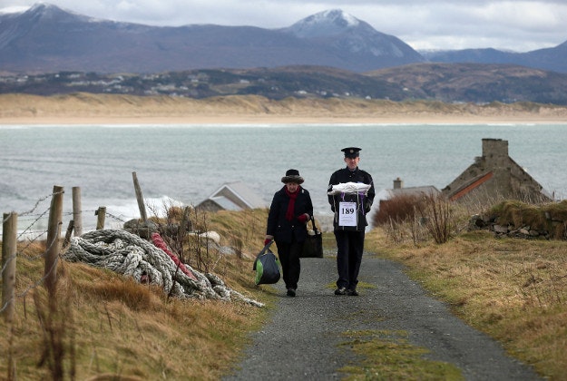 Presiding Officer Carmel McBride and Garda Sergeant Paul McGee carry a ballot box away from a polling station after voting concluded on the island of Inishbofin. Voters on the remote isle off the coast of Donegal were among the first to cast their ballots in Ireland's General Election, a day ahead of the rest of the country. 