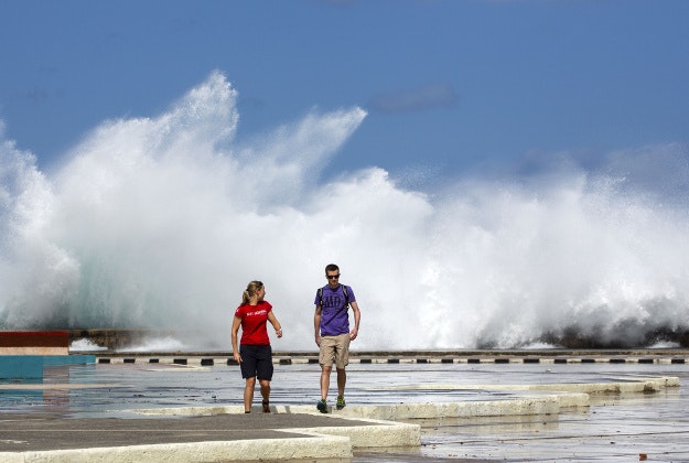 A couple walks away as waves crash against the Malecon in Havana, Cuba, Thursday, Feb. 25, 2016. President Barack Obama said that he will visit Cuba on March 21-22, making him the first sitting president in more than half a century to visit the island nation. 