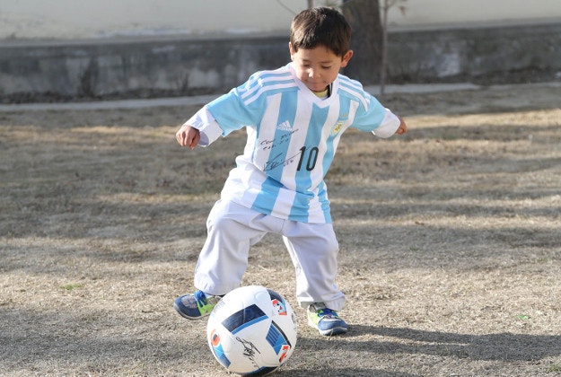 In this provided by UNICEF, Murtaza Ahmadi, an Afghan Lionel Messi fan, wears a donated and signed shirt by Messi, in Kabul, Afghanistan, Thursday, Feb. 25, 2016. 
