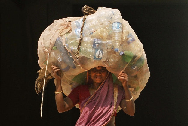 An Indian woman carries a sack of used plastic bottles to be sold at a recycled plant on the International Womans Day in the eastern Indian city of Bhubaneswar, India, Tuesday, March 8, 2016. 