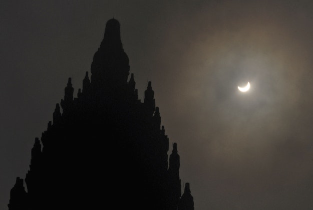 A partial solar eclipse is seen behind the 9th century Prambanan Temple in Yogyakarta, Indonesia, Wednesday, March 9, 2016. The rare astronomical event is being witnessed Wednesday along a narrow path that stretches across 12 provinces encompassing three times zones and about 40 million people. 