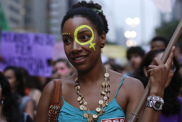 An activist attends a demonstration to mark International Women's Day, in Sao Paulo, Brazil, Tuesday, March 8, 2016. International Women's Day celebrated women and their accomplishments, but it also offered a stark reminder of the gender divides in rights, representation and pay.